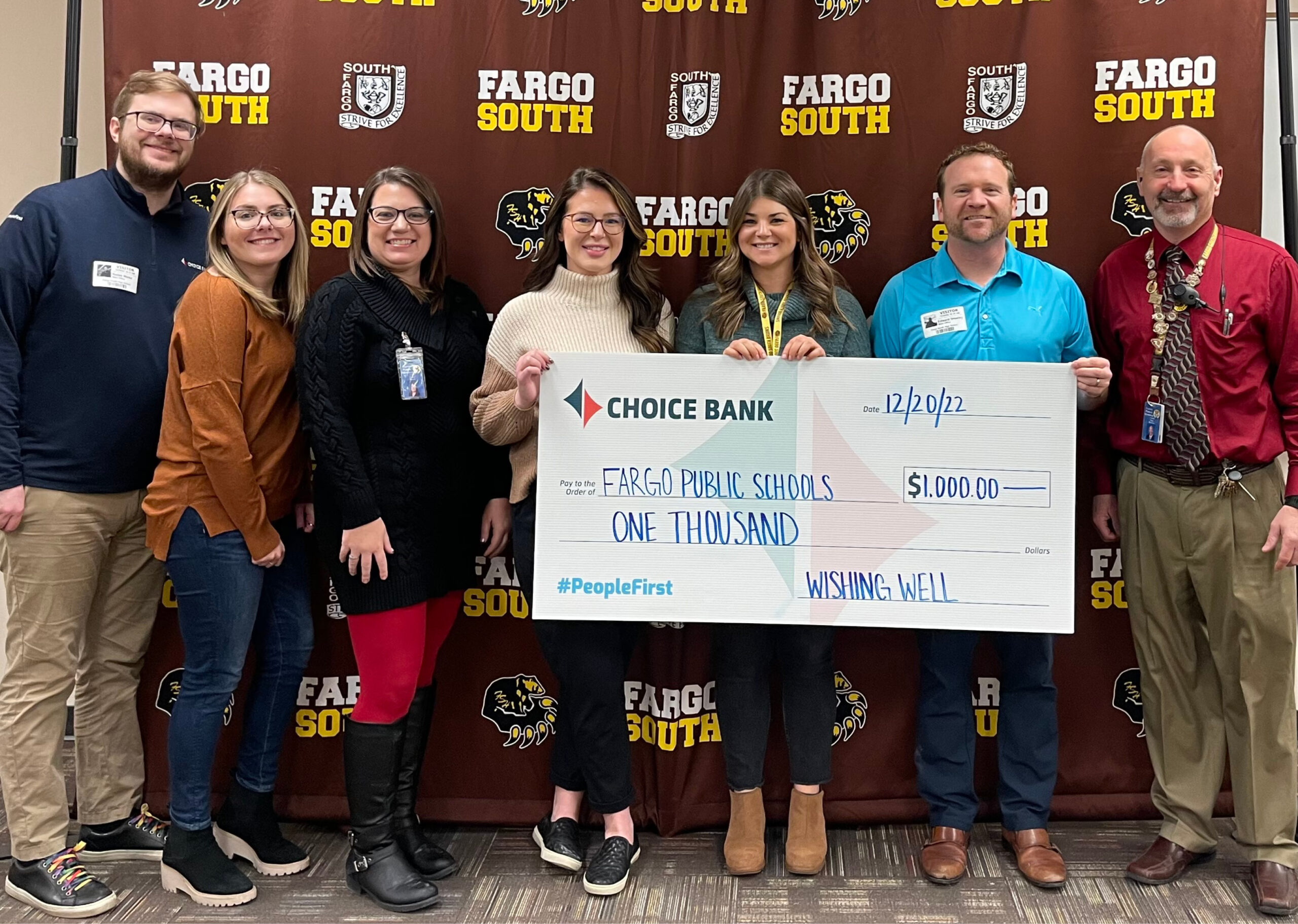 Men and women hold giant donation check