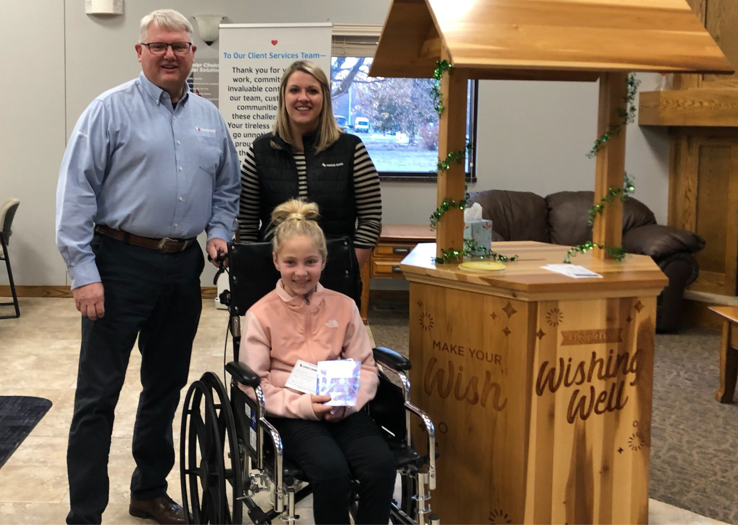 Young girl in wheelchair with two adults standing behind her